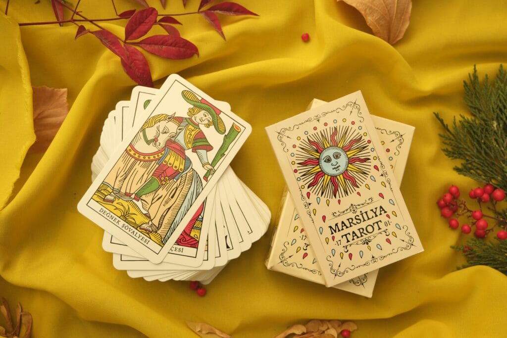 Marseille Tarot cards arranged on yellow fabric, featuring artistic design and nature accents.