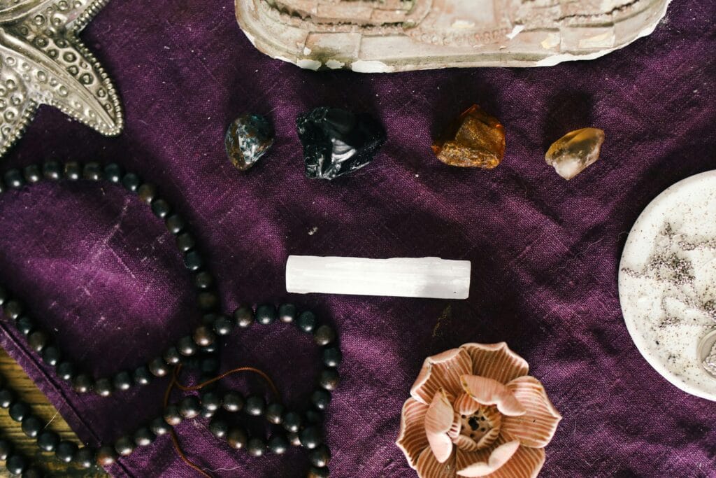 A still life featuring crystals, beads, and accessories on a purple fabric.