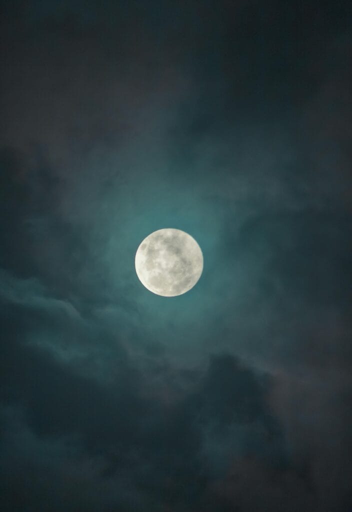 A mesmerizing full moon illuminating the dark clouds at night, creating a dramatic celestial scene.